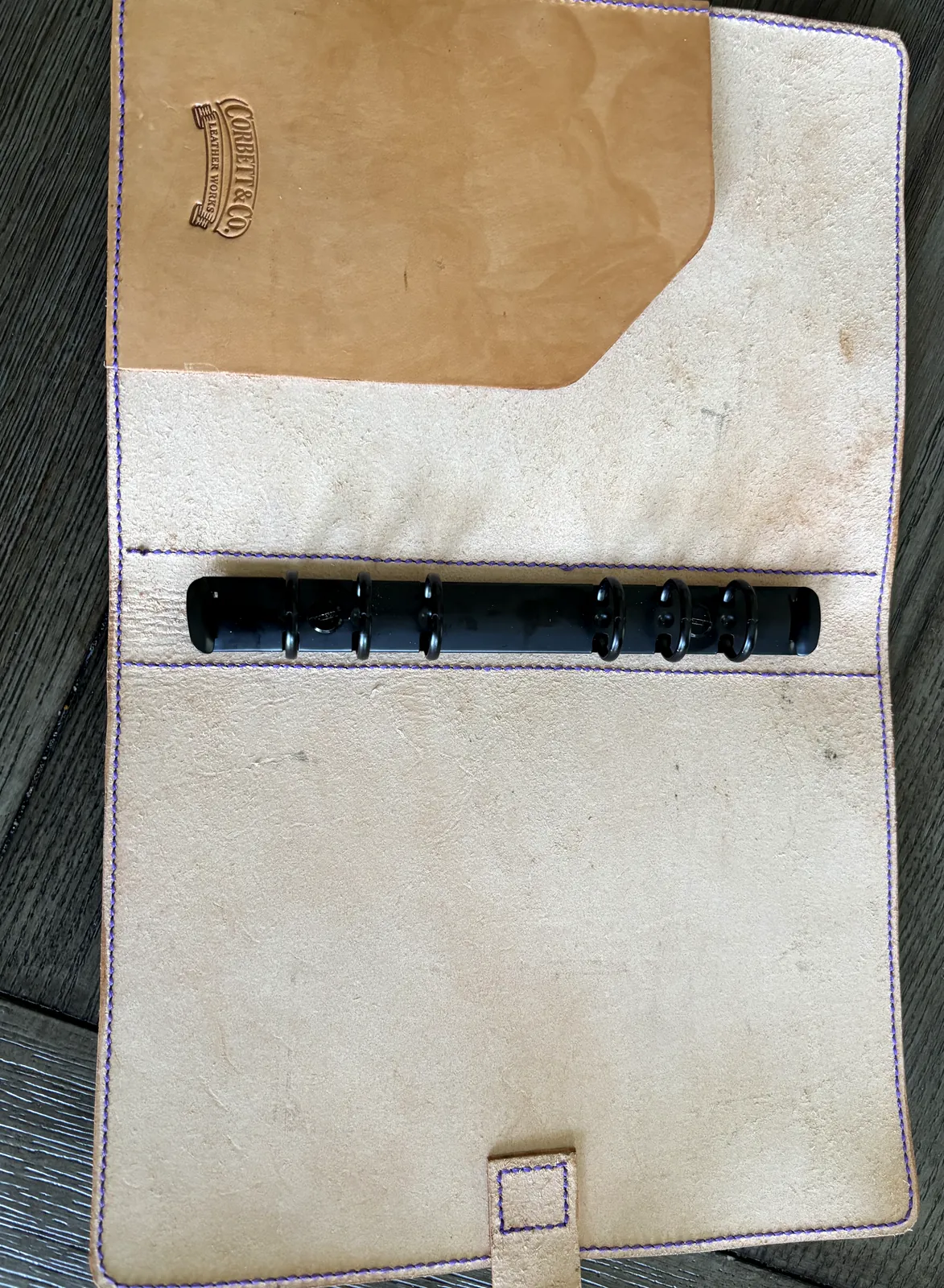 Open 6-ring leather notebook cover with purple stitching and embossed logo