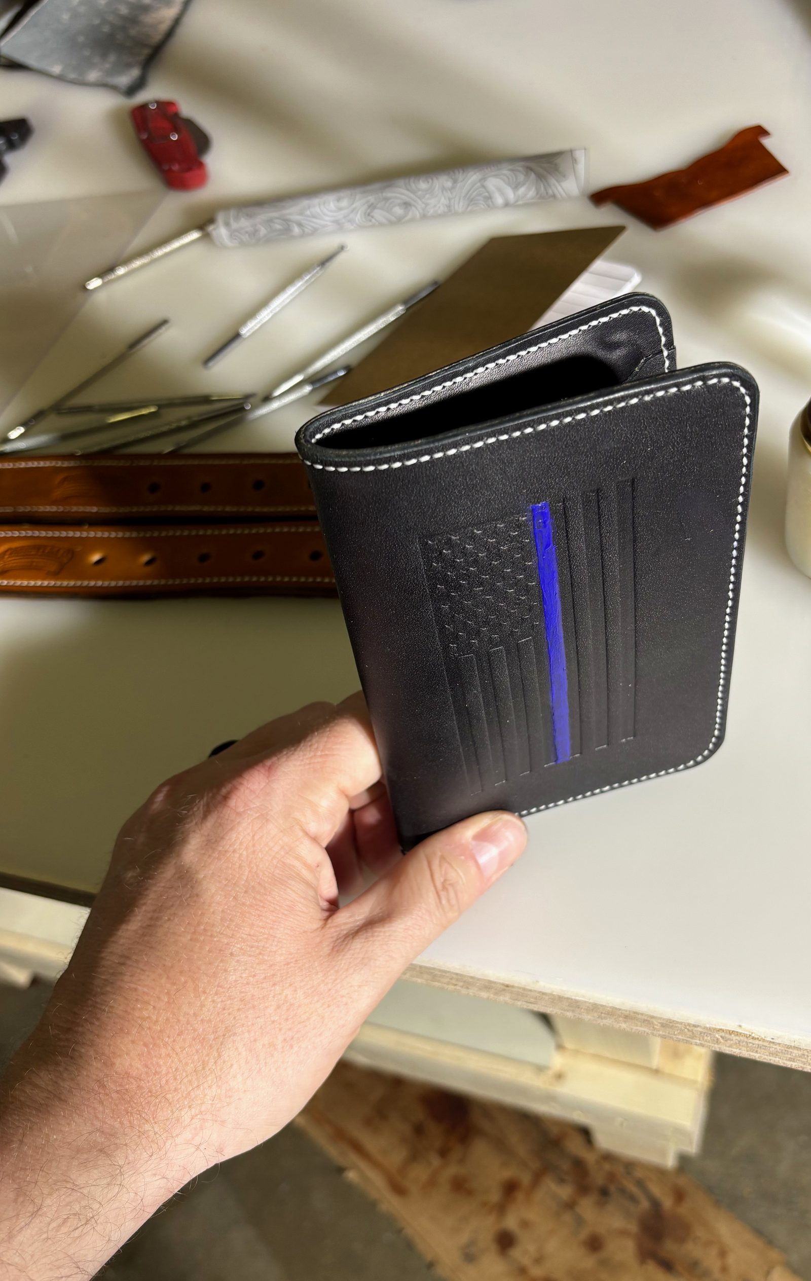 The Blue Line Passport held above tooled Heritage Belts on the workbench