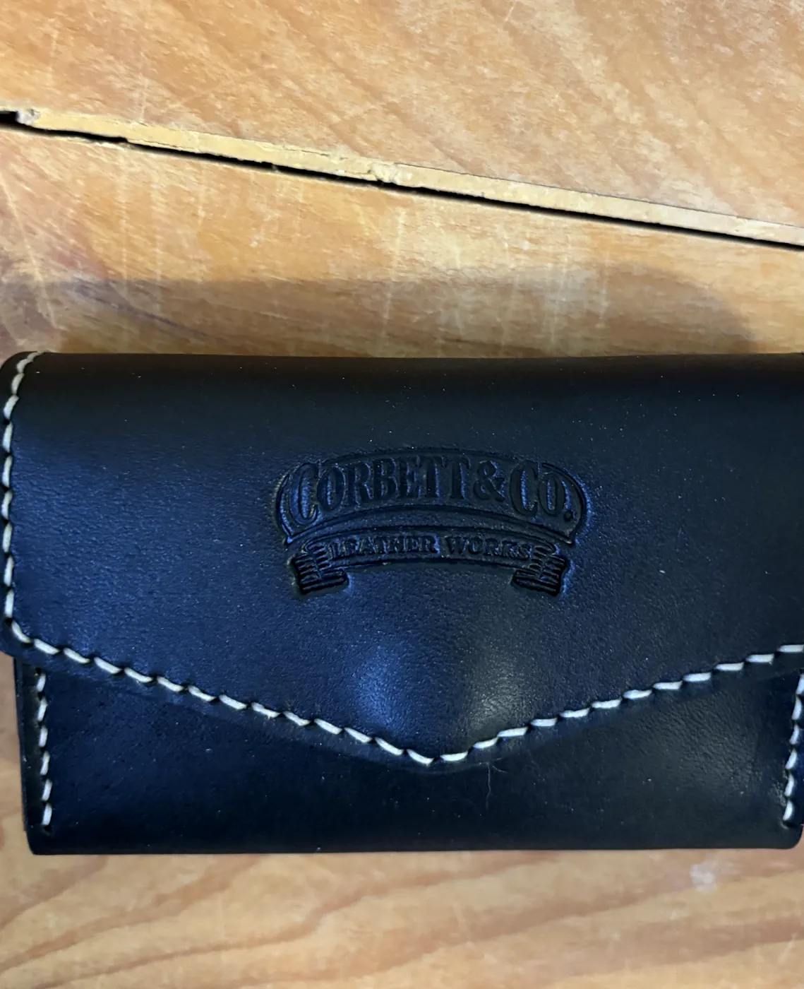 Black leather business card holder with embossed maker's mark and white stitching