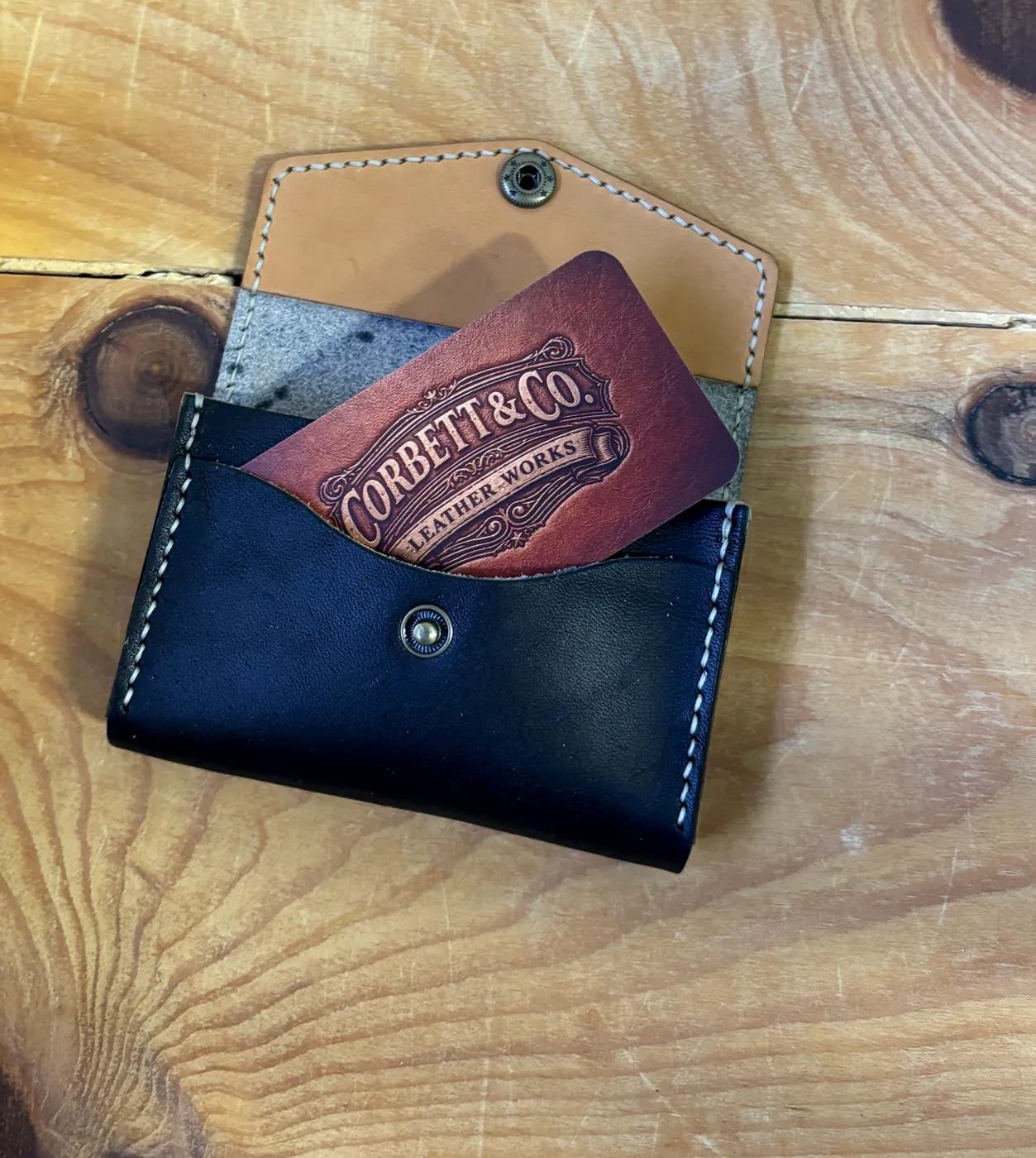 Open business card holder with brand card in the pocket and tan interior