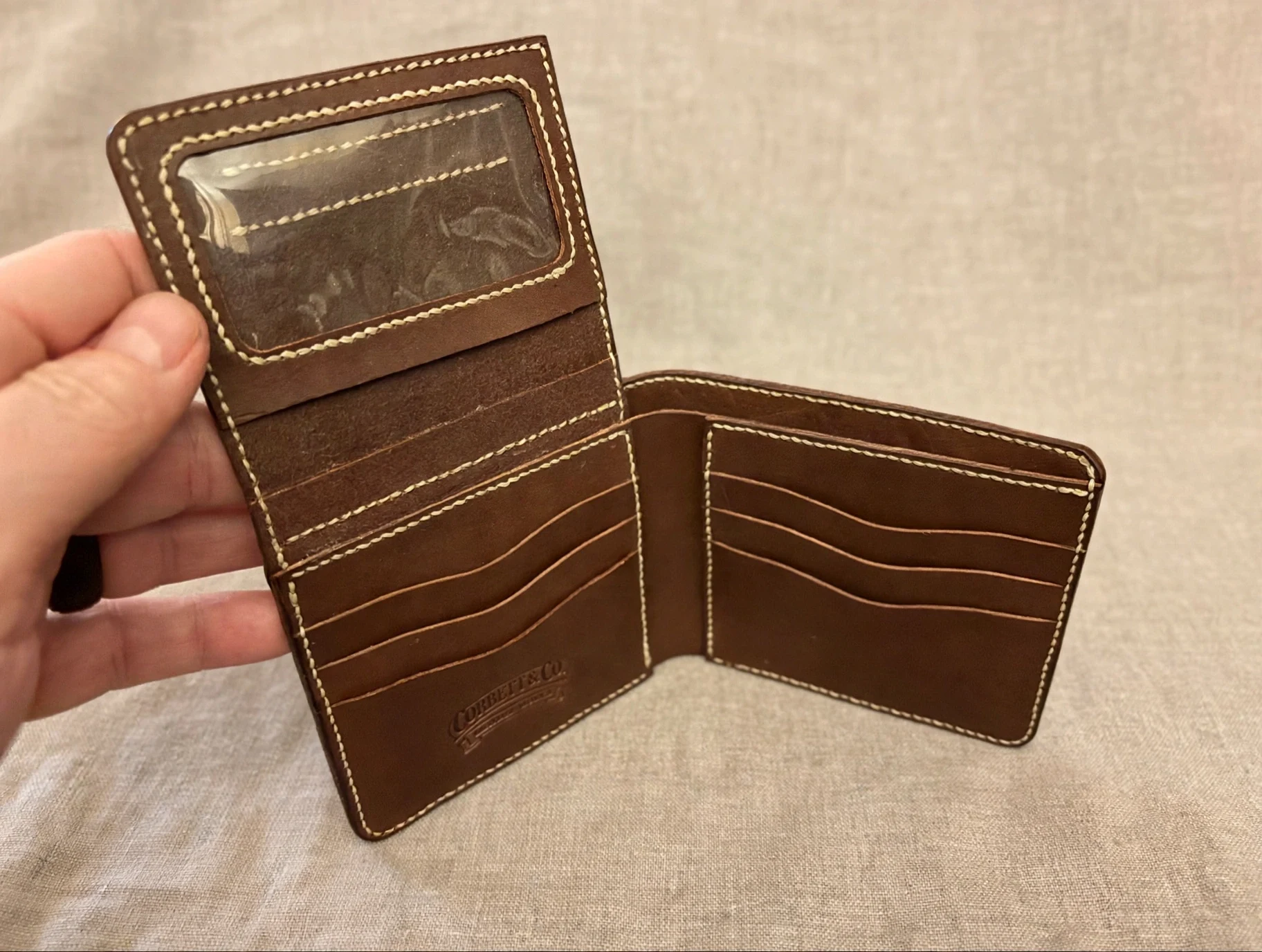 Handmade alligator bifold wallet held in hand for scale