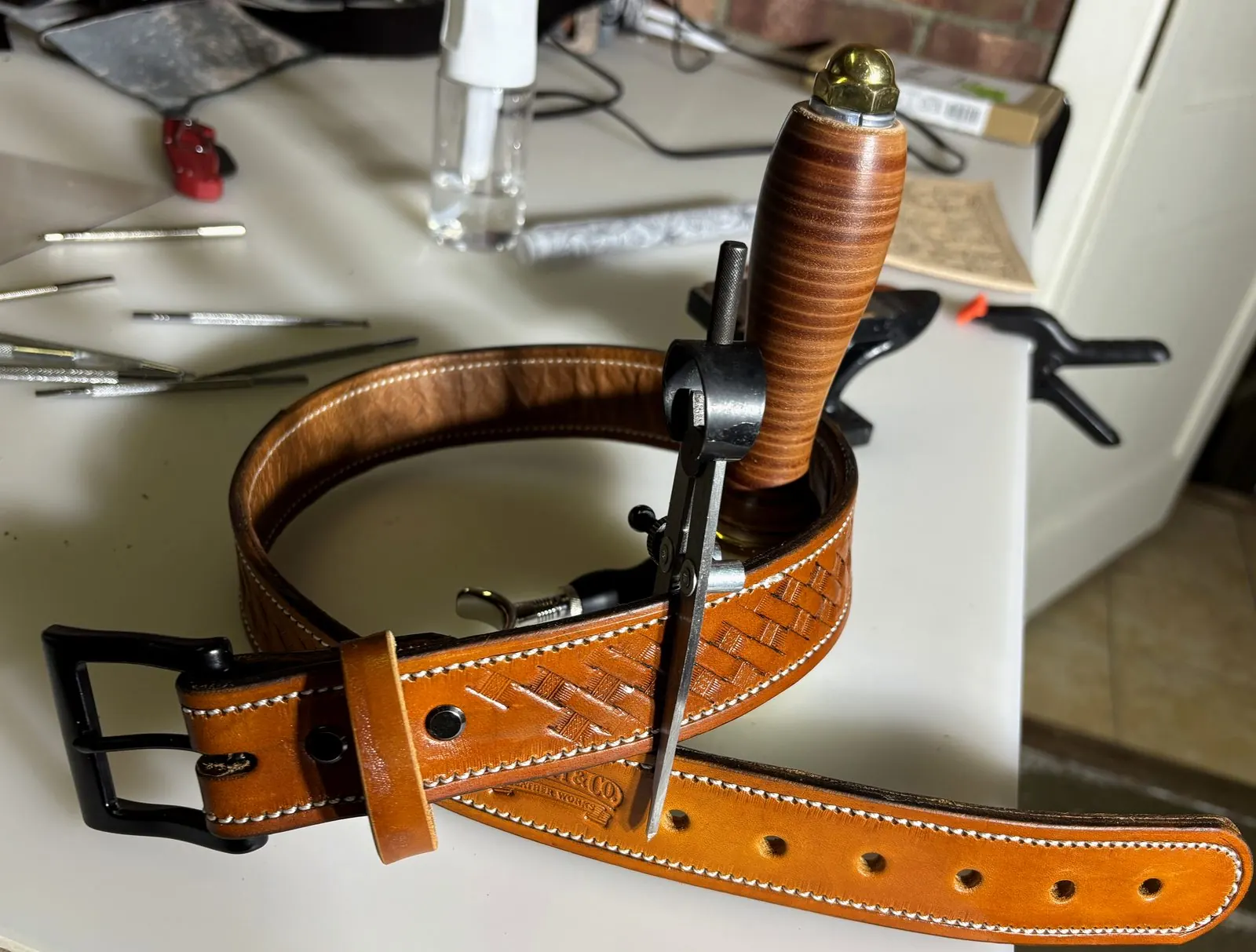 Basketweave tooled leather belt coiled on the workbench