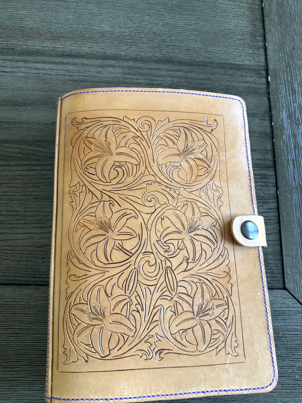 Hand-tooled floral leather notebook cover with purple contrast stitching