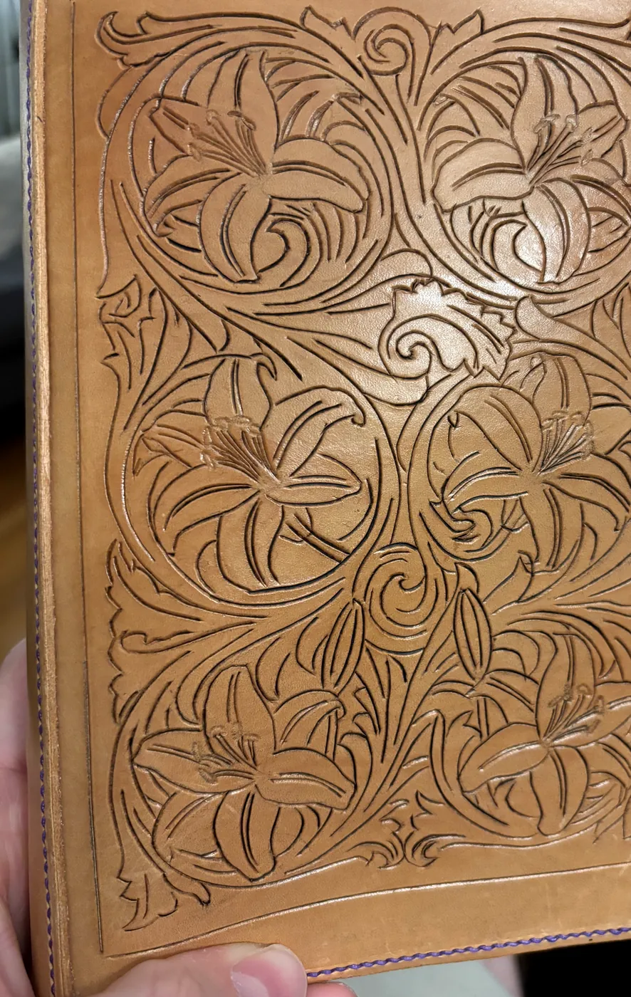 Close detail of hand-tooled lily and vine carving on leather