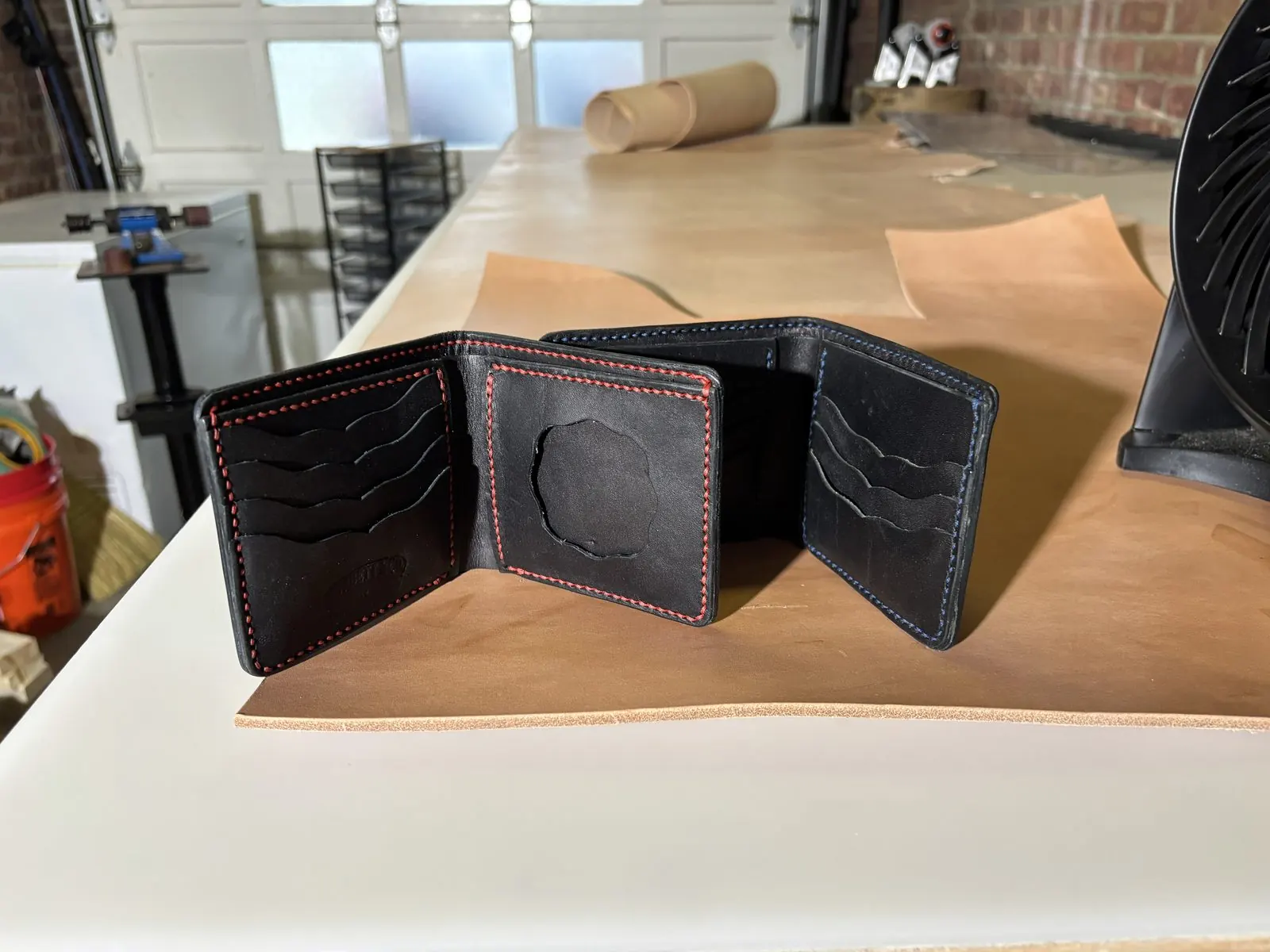 Two leather bifolds side by side with red and blue contrast stitching